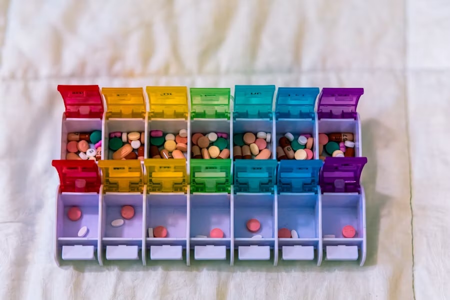 A colorful weekly pill organizer filled with various types of medication arranged in compartments.